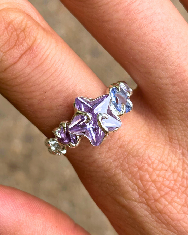Silver ring with purple gemstones on a finger