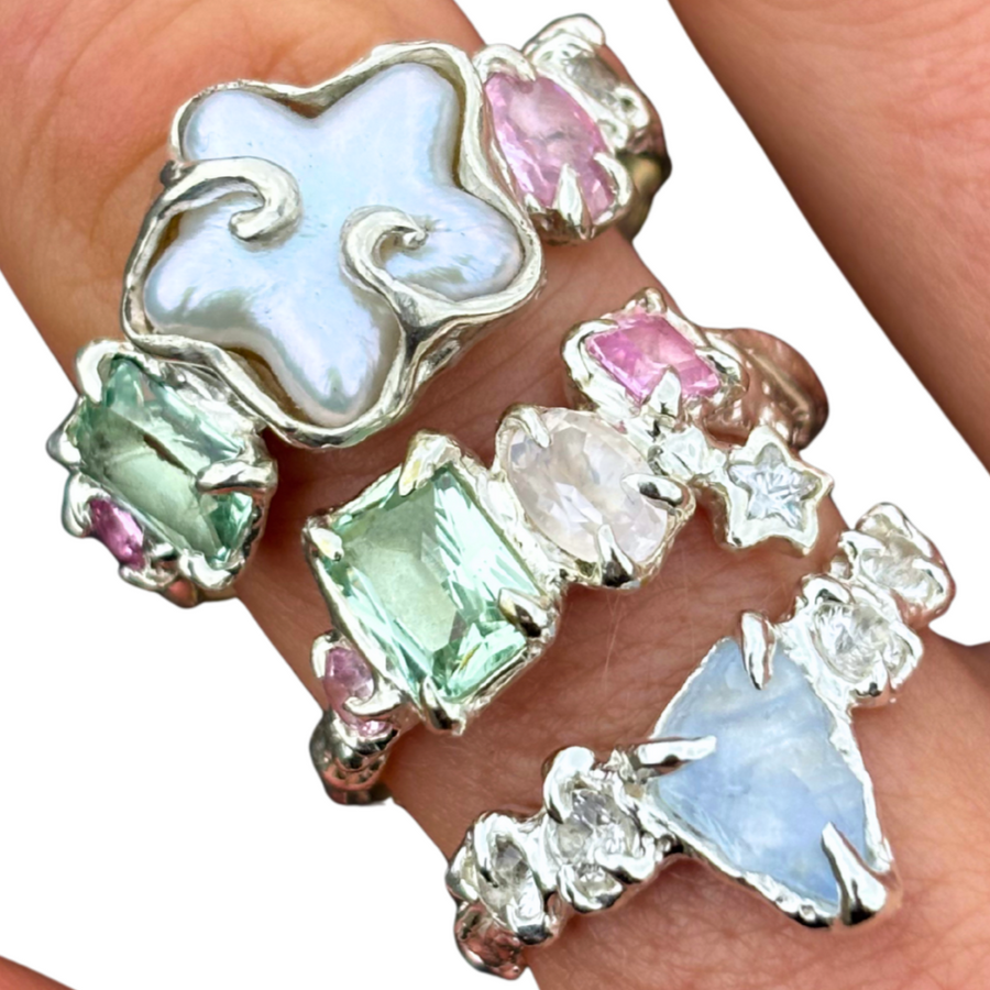 Close-up of a hand wearing a silver ring with colorful gemstones.