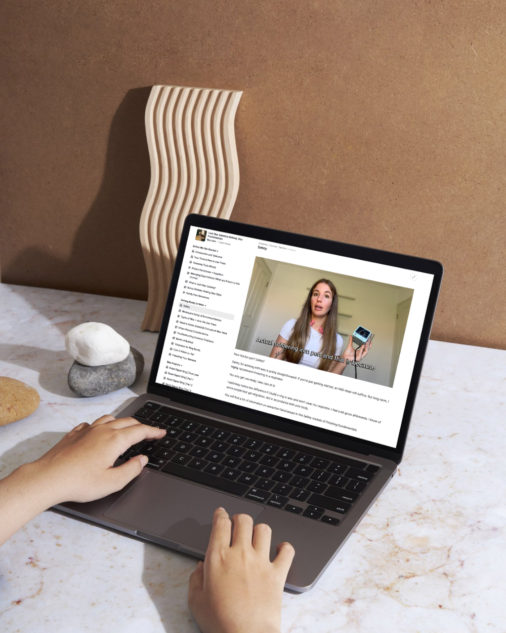 Person using a laptop on a marble surface to learn Lost Wax jewellery making.